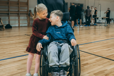 happy disabled boy in wheelchair looking at girl in dance studio with mirrorのeditorial素材
