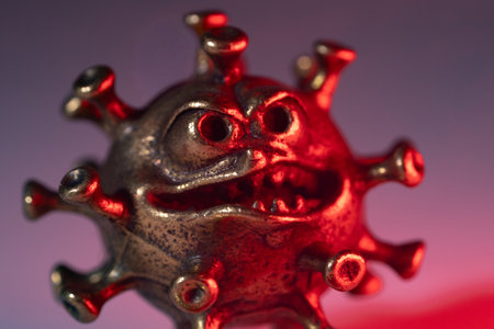 Close-up of a metallic virus model, highlighted by red lighting, emphasizing its unique textures and features, symbolizing health concerns and infectious diseasesの写真素材