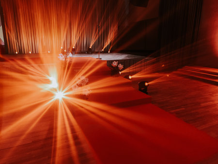 Red carpet on the stairs in the hall of the theater with bright rays of light.の写真素材
