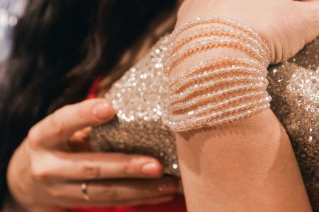 Stylish female figure in a shimmering dress with sequins and a beaded bracelet, highlighting elegance and sophistication in a chic environment with warm tonesの写真素材