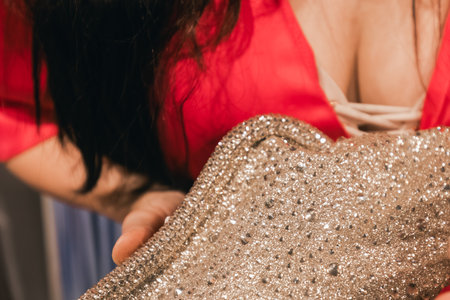 Female figure in red dress presents sparkling gold material, highlighting textures and elegance, set against a stylish backdrop of a contemporary fashion spaceの写真素材