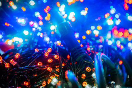 Brightly colored string lights with blue, red, and yellow bulbs are artistically tangled, enhancing the festive ambiance for celebrations and joyful momentsの写真素材