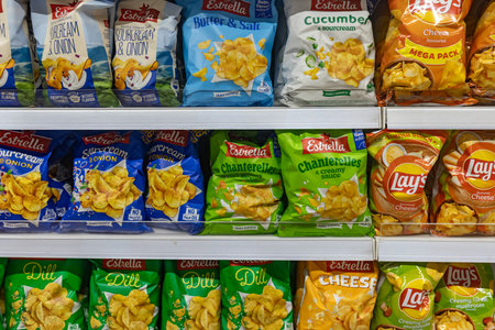 Valmier, Latvia - November 24, 2025: Estrella and Lay's potato chips are arranged on a supermarket shelf, highlighting colorful packaging and diverse flavorsのeditorial素材