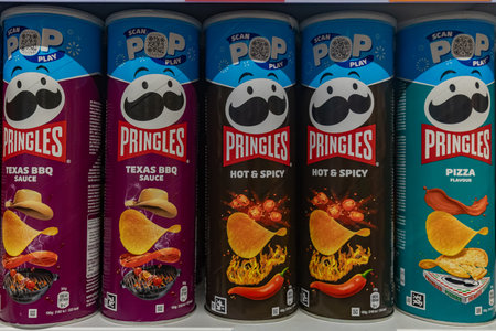 Valmier, Latvia - November 24, 2025: Pringles snack cans display Texas BBQ, Hot & Spicy, and...