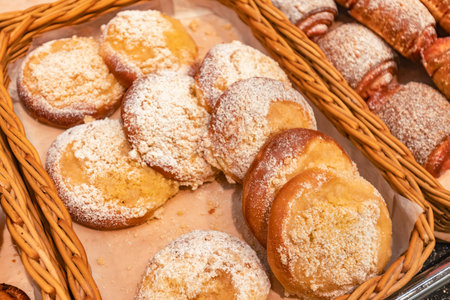 Assorted pastries dusted with powdered sugar are beautifully displayed in a woven basket, inviting...