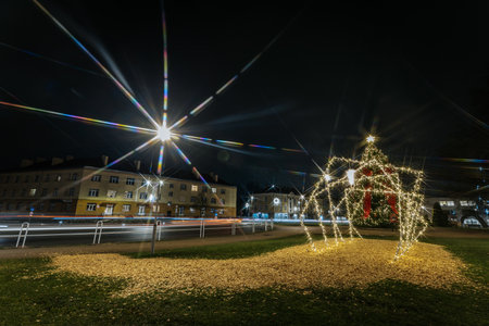 Brightly lit reindeer decoration stands in grassy area at night, surrounded by buildings and festive lights, enhancing the joyful holiday ambianceのeditorial素材