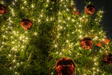 Festive Christmas tree decorated with bright lights and red ornaments, creating a warm ambiance, ideal for holiday celebrations and joyful gatheringsの写真素材