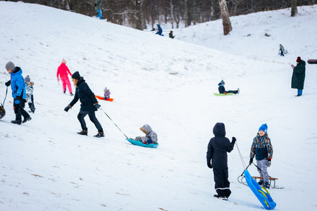 Valmiera, Latvia - January 02, 2026: Families and children are sledding down snowy hill, enjoying...