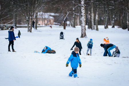 Valmiera, Latvia - January 02, 2026: Kids in vibrant winter outfits are playing in the snow at a...