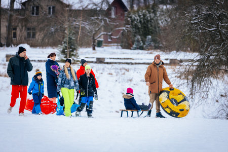 Valmiera, Latvia - January 02, 2026: Families with children are participating in winter fun, carrying sleds and inflatable tubes in a snowy environmentのeditorial素材