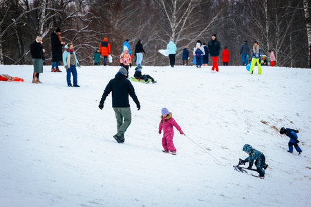 Valmiera, Latvia - January 02, 2026: Families are having fun in snowy park, children sledding down hill while adults watch, creating a joyful winter sceneのeditorial素材