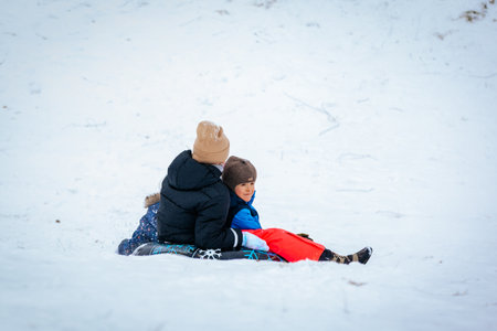 Valmiera, Latvia - January 02, 2026: African American boy and Caucasian girl are sledding together...