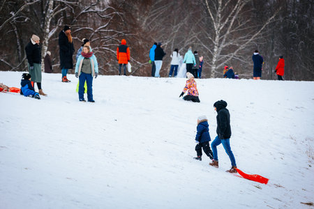 Valmiera, Latvia - January 02, 2026: Families are having fun in the snow, sledding down the hill,...