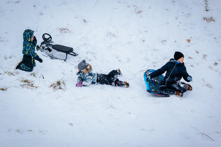 Valmiera, Latvia - January 02, 2026: Children playing in the snow, sledding and enjoying winter activities on a snowy hill with a bright atmosphereのeditorial素材