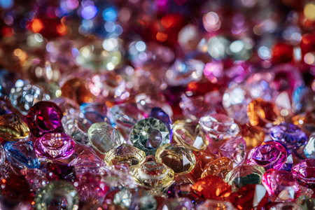 Assorted sparkling gemstones and crystals in various colors and shapes create a vibrant display of light and color on a textured surfaceの写真素材