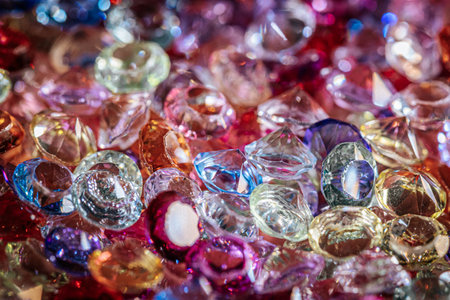 Assorted sparkling gemstones and crystals in multiple colors and shapes are arranged on a textured surface, reflecting light and creating a vibrant visual effectの写真素材