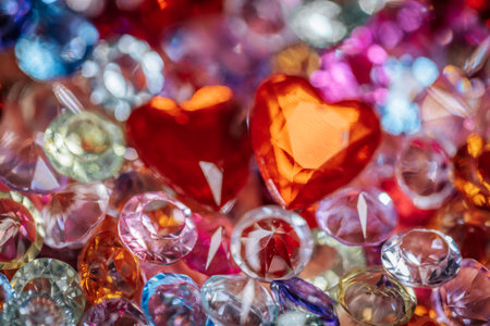 Assorted sparkling gemstones and crystals in various colors and shapes, with two prominent red...