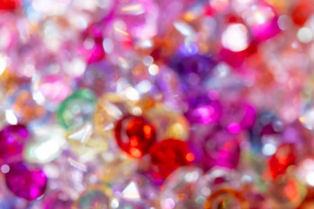 Assorted gemstones and crystals in various colors and shapes create a vibrant, blurred background with sparkling reflections and a colorful display of lightの写真素材