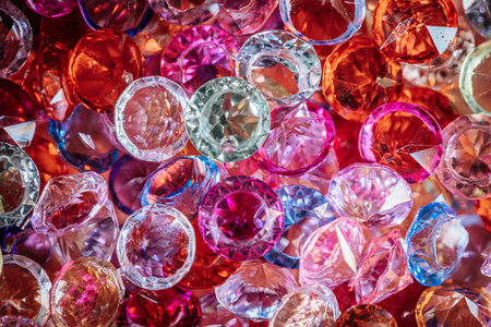 Assorted sparkling gemstones in red, pink, and clear colors are closely arranged, showcasing various...