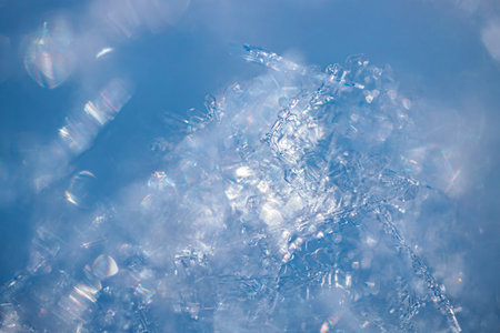 Close-up view of ice crystals with sparkling reflections on a blue background, highlighting the...