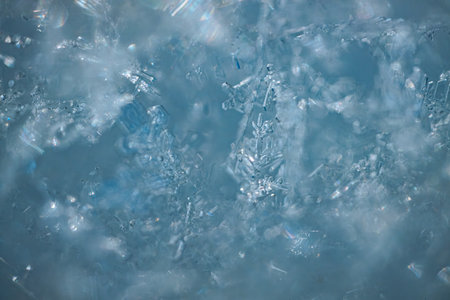 Close-up image of detailed ice crystals on a blue surface, highlighting their unique shapes and...