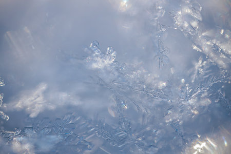Detailed close-up of snowflakes against a soft blue backdrop, highlighting the unique shapes and...