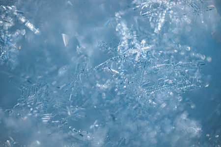 Close-up image of snowflakes with detailed crystalline structures against a soft blue background,...