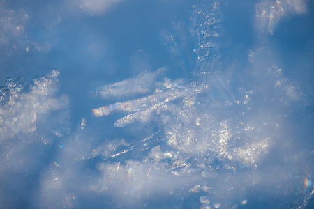 Detailed close-up of snowflakes against a blue backdrop, highlighting their unique shapes and...