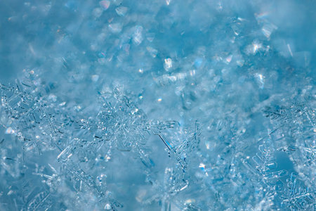 Close-up view of delicate snowflakes against a blue backdrop, revealing unique shapes and textures...