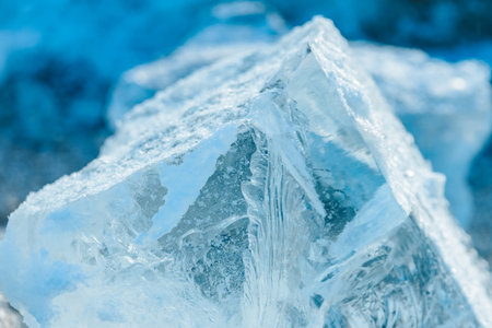 Large ice crystal displays detailed textures and patterns, illuminated by soft blue light, set...