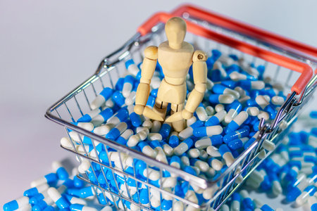 Wooden figure positioned in a shopping basket overflowing with blue and white capsules, set against a minimalistic background for visual contrastの写真素材