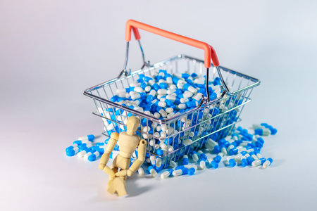 Shopping basket overflowing with blue and white capsules, with a wooden mannequin figure leaning against it on a light backgroundの写真素材