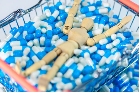 Wooden figure positioned among blue and white capsules inside a shopping basket, illustrating themes of health and wellness in a pharmaceutical settingの写真素材