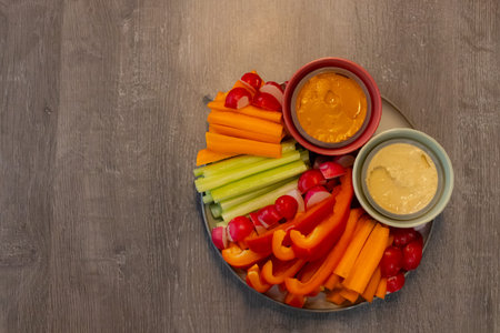 Fresh vegetables such as carrots, celery, bell peppers, and cherry tomatoes arranged on a round...