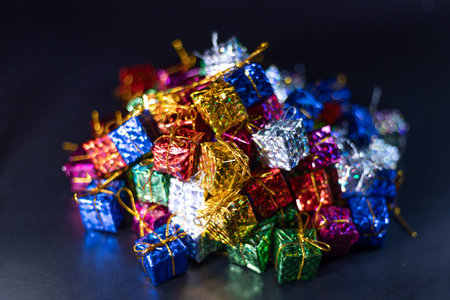 A collection of vibrant, metallic gift boxes in various colors piled together, creating a festive...