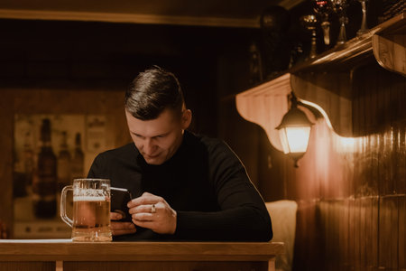Valmiera, Latvia - March 06, 2026: Male individual in a black sweater engages with his smartphone...