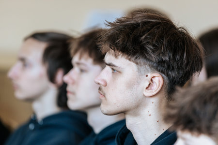 Valmiera, Latvia - March 17, 2026: Young men with short hairstyles in hoodies focused on a seminar...