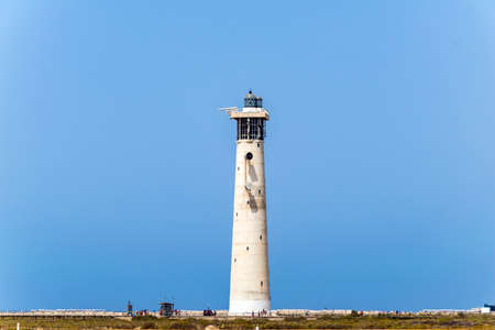 Faro de Morro Jable, at european lighthouse located on one of the most famous beaches on Fuerteventura. Landscape with absolutely clear blue sky and the historical buildingの写真素材