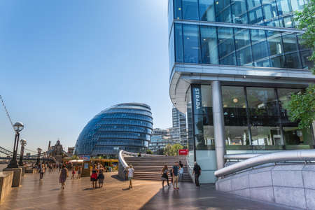 LONDON, UNITED KINGDOM - AUGUST 23, 2016: Walkway at Southwark Banks with people and view of the modern city hall building and office building on Thames River in London, England, UK. Queens Walkのeditorial素材
