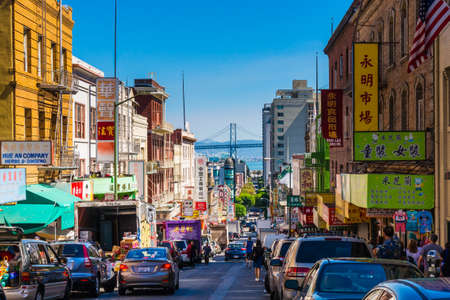 San Francisco - September 20, 2015: Downtown city life in a busy street of Chinatown San Francisco. View with many people, shops and cars - lookout to the Oakland Bay Bridge.のeditorial素材