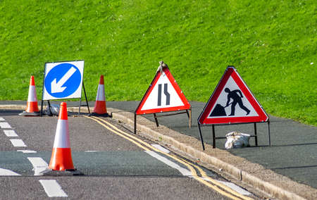 signs and traffic cones set up on the roadの写真素材