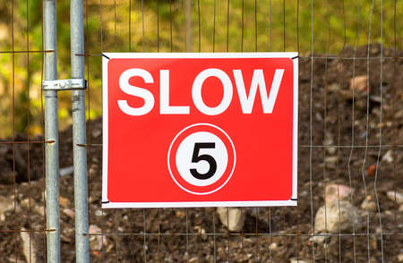 Low speed limit for safety is posted at five miles per hour.A red sign hanging on a metal fence .の写真素材