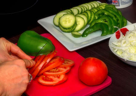 Woman hands the cutting fresh tomatoes and cucumbers on the salad vegetableの写真素材