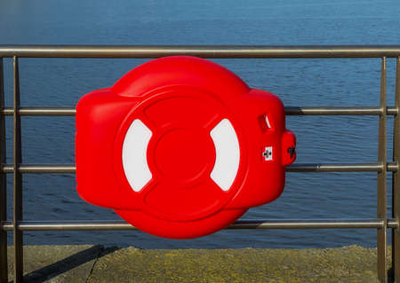 Lifebuoy enclosed in plastic cover hanging on the pier in Plymouth, UK.