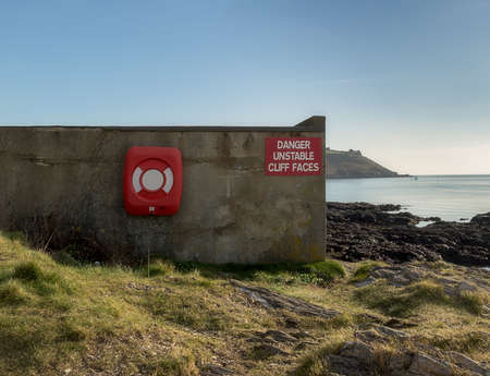 Fragment of a wall of the building standing on the side of the cliff on which hangs a red warning...