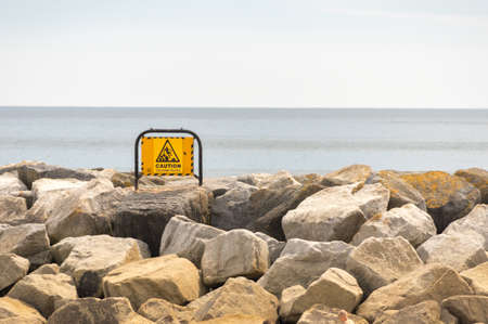 Warning sign set on the stones on the sea front.の写真素材