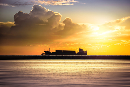 Cargo ship in the ocean at sunset sky, Silhouette of the ship on a sunset, Industry Container cargo ship at coast in sunset sky, Transportation, Shipping, Logistics.の写真素材