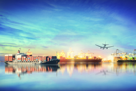 Logistics and transportation of international container cargo ship and cargo plane with ports crane bridge in harbor at sunset sky for logistics import export background and transport industry.の写真素材