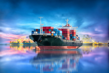 Logistics and transportation of international container cargo ship with port crane bridge in seaport at twilight sky for logistics import export background and transportation industryの写真素材