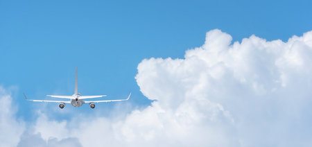 Commercial airplane flying above clouds on day light, Clear blue sky and fluffy soft white cloud with copy space, Travel vacation trip conceptの写真素材